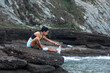 © Pablo Garcia/ADDICTIVE STOCK - Side view of fit female athlete sitting on rock on beach and stretching legs while doing forward bend exercise during workout