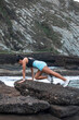 © Pablo Garcia/ADDICTIVE STOCK - Side view of sporty female balancing in plank position during intense training on rocky seashore in summer