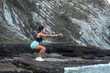 © Pablo Garcia/ADDICTIVE STOCK - Side view of focused female athlete in activewear doing squats while training on rocky coast near sea and looking away