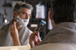 © Philippe Degroote/ADDICTIVE STOCK - Stock photo of middle aged man with grey hair using shaving cream to shave his beard.