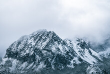 Majestic Panoramic Scenery Of Rough Rocky Slopes Of Mountain Range Covered With Snow Under Cloudy Sky
