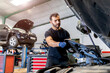 © Sergio Victor Vega/ADDICTIVE STOCK - Low angle of busy male master taking off plastic protective cover from car engine while fixing vehicle in workshop