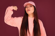 © Victor Torres/ADDICTIVE STOCK - Portrait of funny young asian woman in the studio looking at camera and showing biceps. She is wearing pink clothes over garnet background