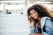 © Xavier Lorenzo/ADDICTIVE STOCK - Young black female with curly hair leaning on hand in trendy outfit and glasses looking at camera while sitting on city street