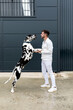 © Sergio Victor Vega/ADDICTIVE STOCK - Side view of cheerful male owner embracing with Harlequin Great Dane while standing on street in city
