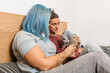 © Txema Gerardo/ADDICTIVE STOCK - Side view of delighted tattooed woman holding Sphynx cat with plump girlfriend resting on bed at home together