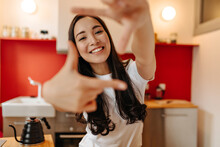 Lady Poses In Kitchen And Shows Off Camera. Portrait Of Charming Asian Woman