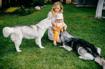 Wall Mural - Mother and son playing with two dogs in the garden