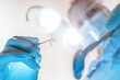 Zahnarzt / Zahnärztin mit Sonde und OP Leuchte aus Sicht des Patienten dicht über dem Mund bei der Untersuchung mit Corona Maske