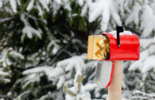 Red Mailbox With Gift Box Inside In Snow Near Pine Tree