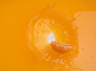 Wall Mural - falling of orange piece into juice,splash orange juice