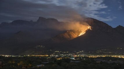 Wall Mural - Timelapse of Clouds Moving Above Wildfire and City Lights at Night. Burning Hill and Sky on Moonlight