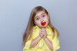 valentine's day caucasian child holding a lollipop heart over grey background.Surprised face.Donation,heart health,world heart day, world health day,world mental health day.Health and heart concept.