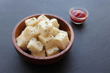 Indian popular Gujrati breakfast dish White Dhokla, Khatta Dhokla, Rice and Urad Dal Khaman. Also known as Instant Rava Dhokla. served with ketchup over black background. copy space.