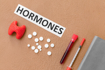 Word HORMONES, thyroid gland, blood sample, syringe and pills on color background