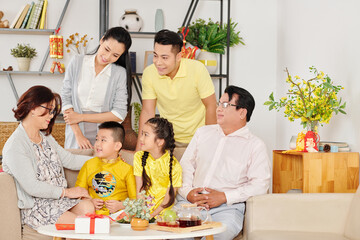 Vietnamese family gathered at home to celebrate Lunar New Year and wish luck to little children in traditional costumer