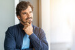 © Joao - Man standing with hand on his chin looking through the window. Successful male portrait with a happy  thinking expression face