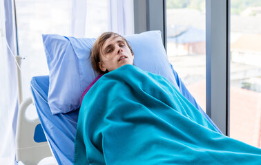 Young man has fever chills patient lies on bed of her shakes in the room hospital background.