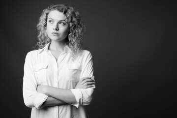 Wall Mural - Young beautiful businesswoman with curly blond hair against gray background