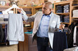 © JackF - Confident young man looking for suit pants in mens clothing boutique