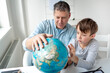 © epiximages - Father learns with child concept. Dad and son get to know the world using a globe.