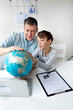 © epiximages - Father learns with child concept. Dad and son get to know the world using a globe.