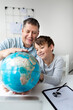 © epiximages - Father learns with child concept. Dad and son get to know the world using a globe.