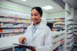 © StratfordProductions - Cheerful female pharmacist using digital tablet at the hospital pharmacy