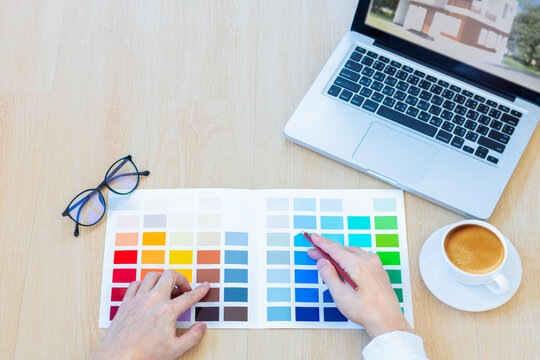 male designer using graphics tablet to choosing color swatch samples chart for selection coloring with laptop computer at workplace