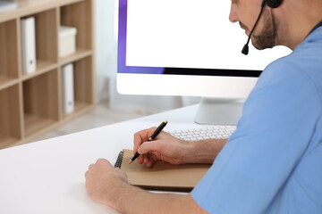 Canvas Print - Doctor with headset consulting patient online at desk in clinic. Health service hotline