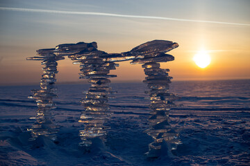 Wall Mural - a sculpture made of pieces of ice against the backdrop of a sunset, on the shore.