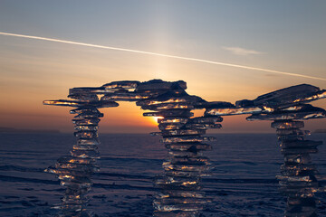 Wall Mural - a sculpture made of pieces of ice against the backdrop of a sunset, on the shore.