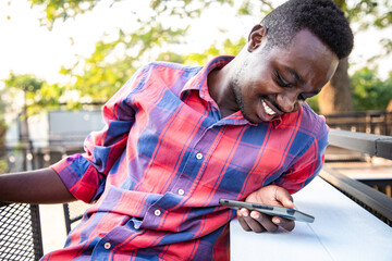 Young handsome American man have bright smile and positive thinking after working hard in the last weekend. He relaxed with smartphone on free time at coffee shop bar.