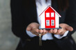 © Kanjana - The red house and the keys are in the agent's hand. Real estate concept Trading, Leasing, Mortgage, Investing.