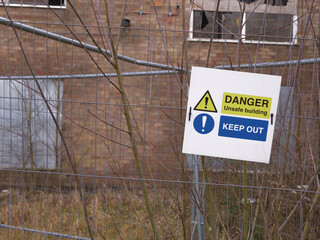 Poster - Danger sign outside derelict urban building after fire