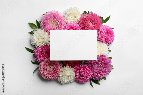 Composition with blank card and beautiful asters on white background, top view. Autumn flowers