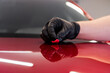 The master removes small dirt pieces from the car bonnet surface with special clay before polishing. Professional car washing and detailing process.
