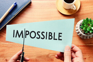 Poster - man hand holding card with the text impossible, cutting the word im so it written possible. success and challenge concept.