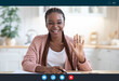 Joyful black woman making video call with laptop in kitchen interior, screenshot