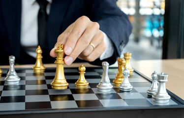 A business man in a suit is holding a chess king figure on the board