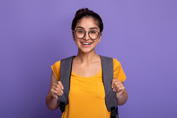 Happy indian female student wearing backpack and eyeglasses