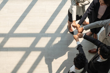 Wall Mural - view from above of multiethnic business team touching hands together as a sign of unity in internation corporate office. diversity in business concept