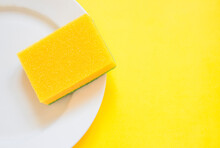 Yellow Sponge On A White Plate On A Yellow Background