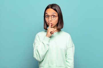 Canvas Print - young hispanic woman looking serious and cross with finger pressed to lips demanding silence or quiet, keeping a secret