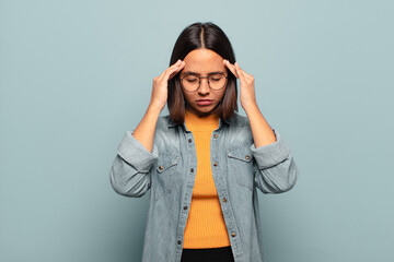 Wall Mural - young hispanic woman looking stressed and frustrated, working under pressure with a headache and troubled with problems