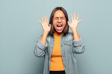 Canvas Print - young hispanic woman screaming in panic or anger, shocked, terrified or furious, with hands next to head