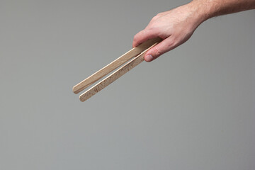 Caucasian male hand holding a wooden tong close up shot isolated on gray background