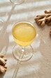 A glass of ginger probiotic drink with fresh ginger root in the background