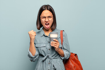 Wall Mural - young hispanic woman shouting aggressively with an angry expression or with fists clenched celebrating success