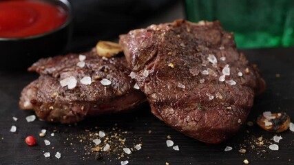 Wall Mural - salt and spices falling on freshly grilled beef fillet steak on black stone restaurant plate